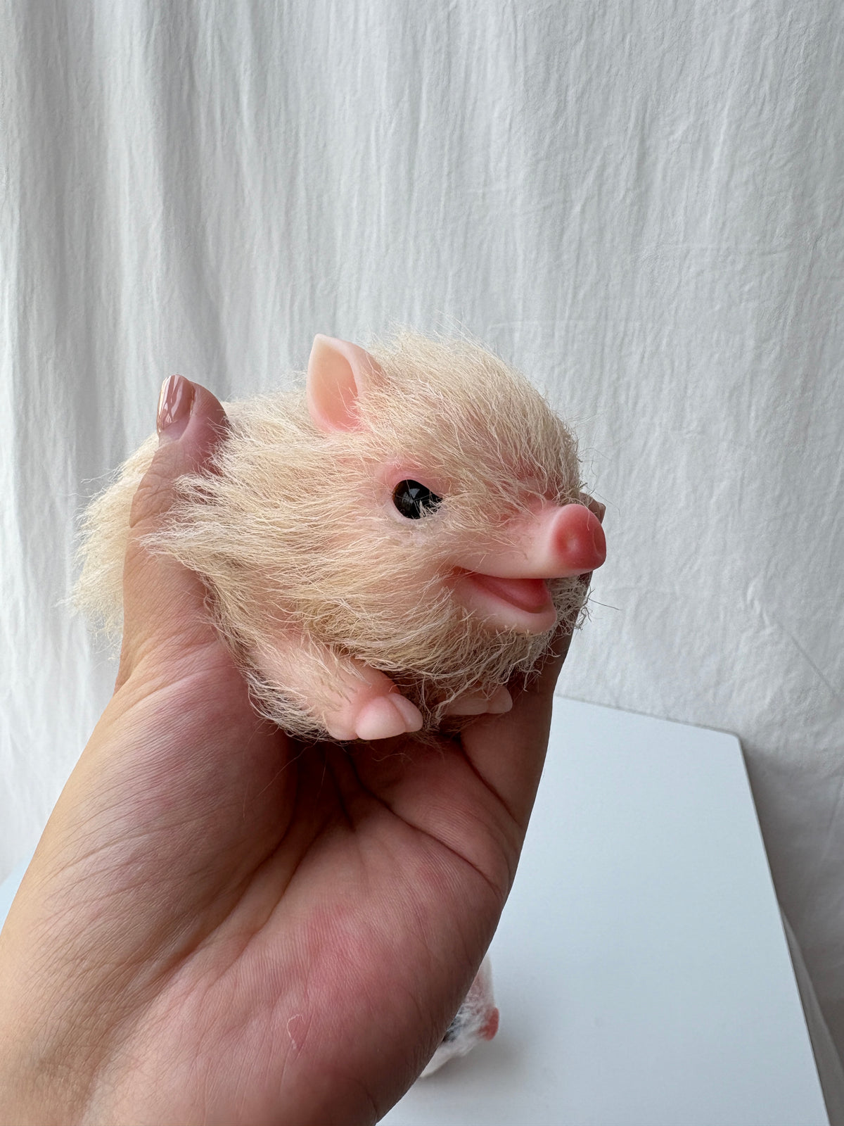 Two miniature silicone pig dolls held in hand