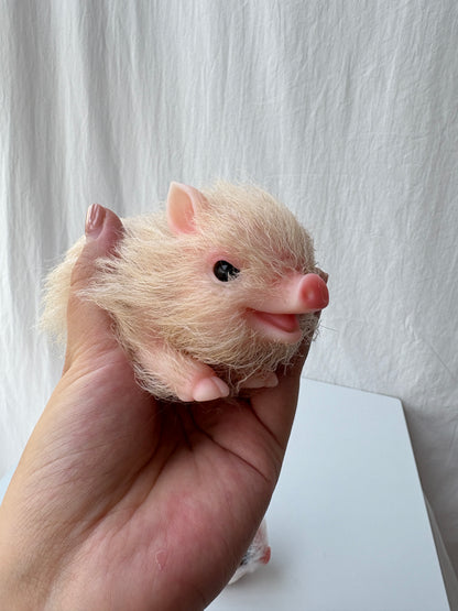 Two miniature silicone pig dolls held in hand